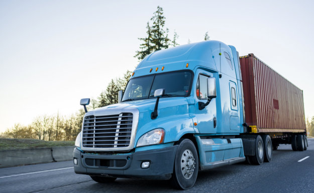 Classic big rig gray semi truck tractor with grille guard transporting commercial cargo