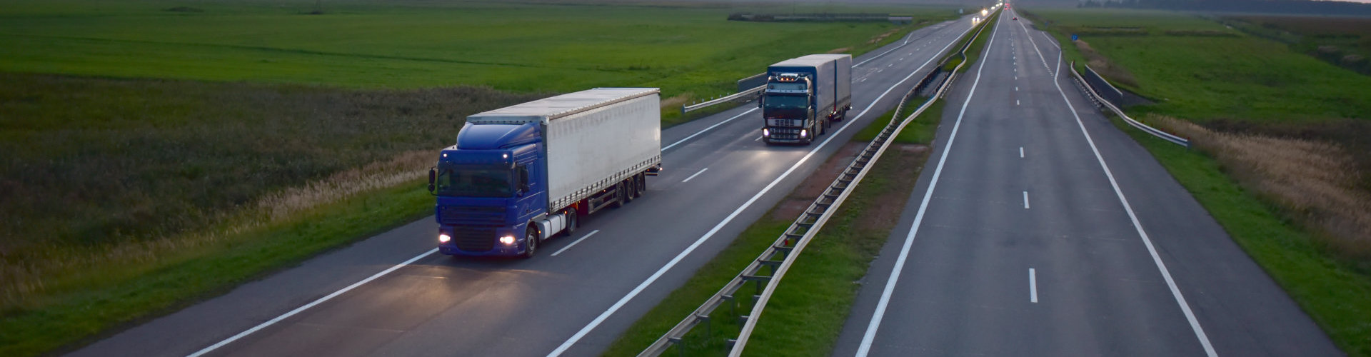 Truck with semi-trailer driving along highway on the sunset background. Goods delivery by roads. Services and Transport logistics. Soft focus, possible granularity.